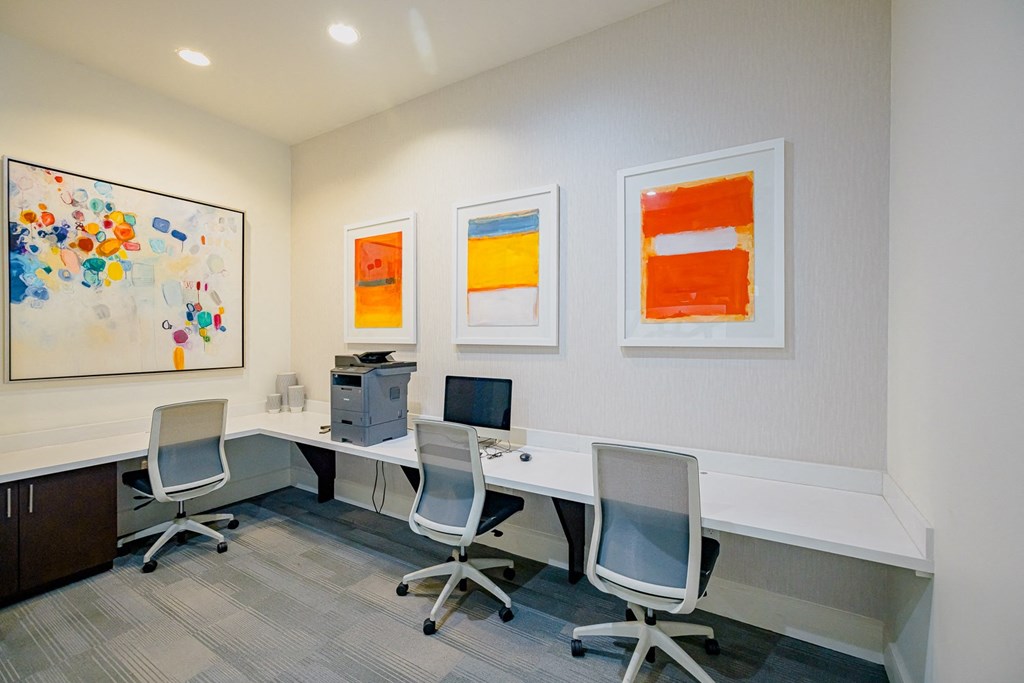 a conference room with three desks and chairs and paintings on the wall