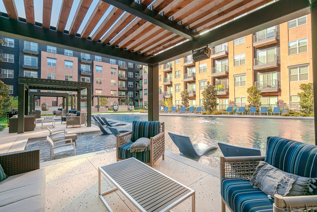 a patio with furniture and a pool in front of an apartment building
