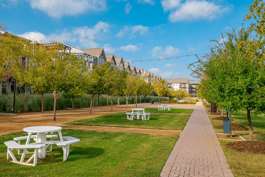 a park with benches and trees in front of a building