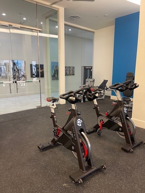Two stationary bikes are in a room with a glass wall.