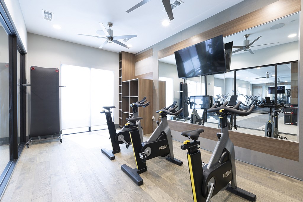 a gym with various exercise bikes and a tv on the wall
