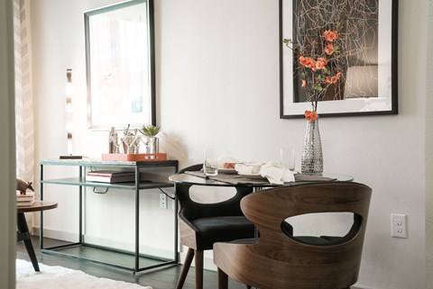 A modern dining room with a glass table and a wooden chair.