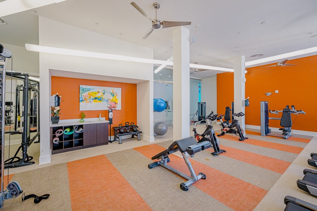 a gym with various machines and weights in a room with orange walls