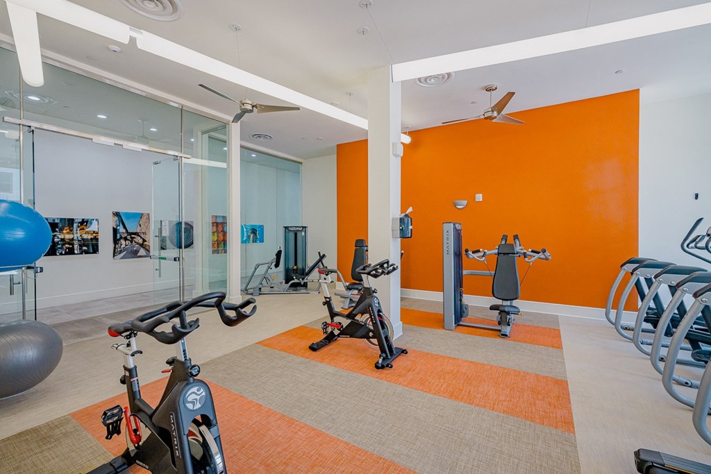 a gym with exercise equipment and an orange wall