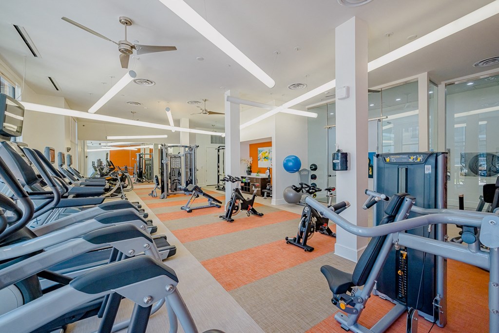 a fitness center with cardio equipment and weights in a building with windows