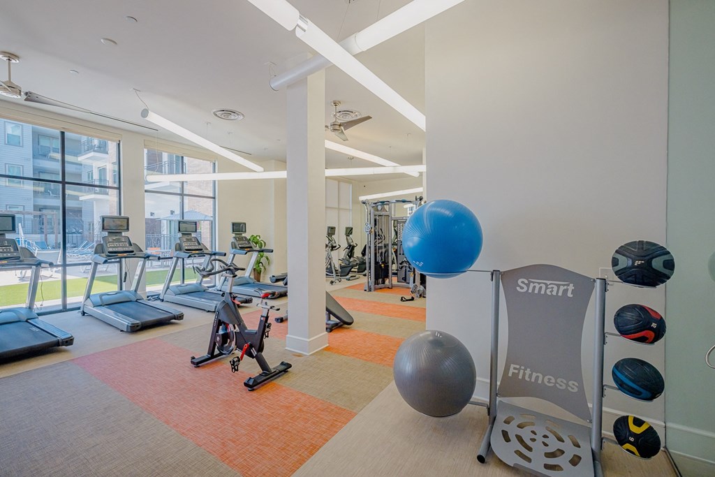 a gym with exercise equipment and windows at the m on hennepin apartments