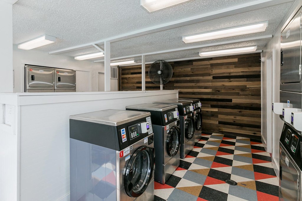 a laundry room with four washing machines and a checkered floor