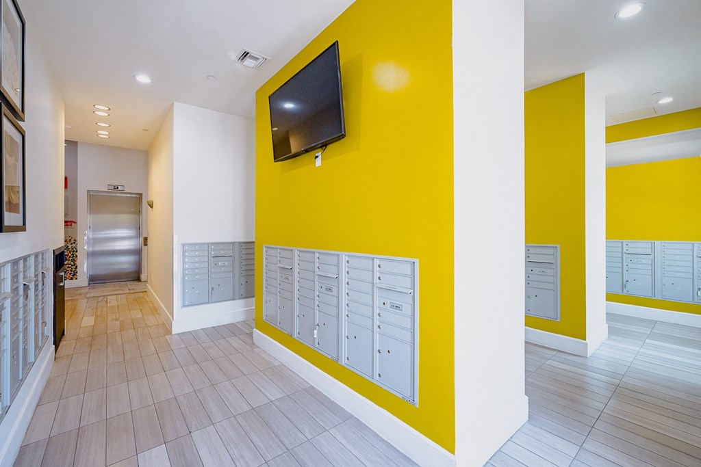 a yellow wall with lockers and a television in a hallway