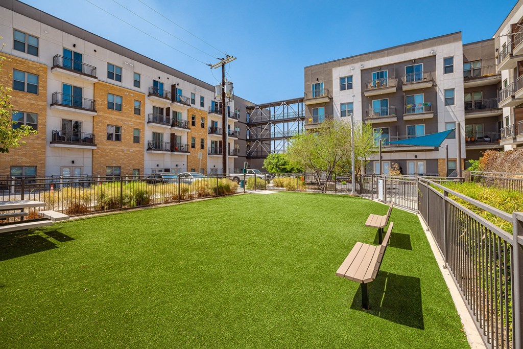 A grassy area with benches in front of apartment buildings.