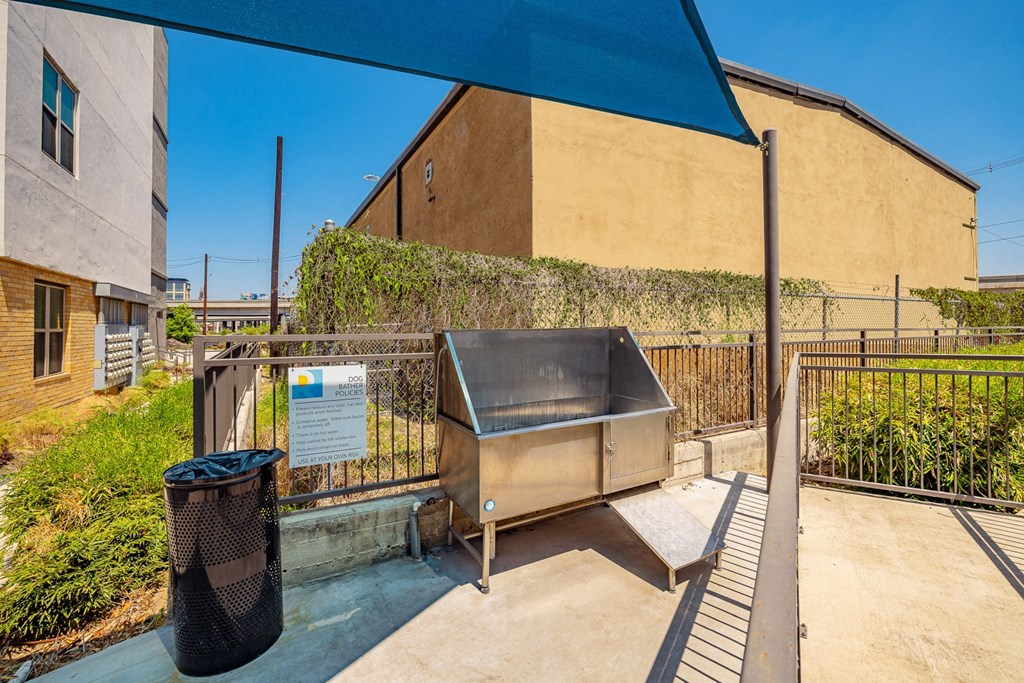 A metal dumpster is in front of a building with a sign on it.