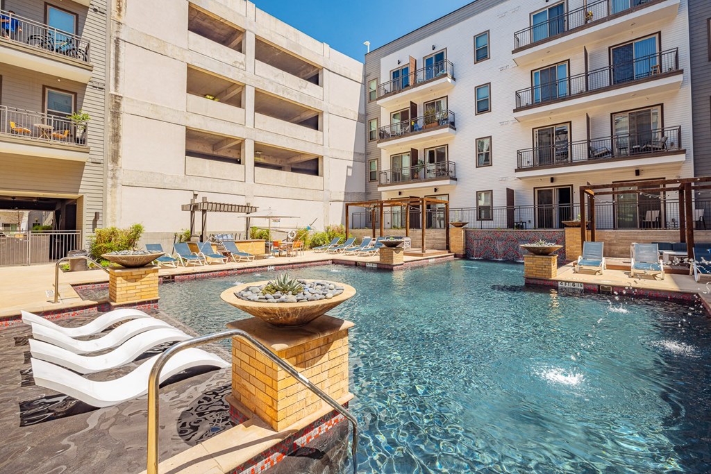 A large outdoor pool with a fountain in the middle of it.