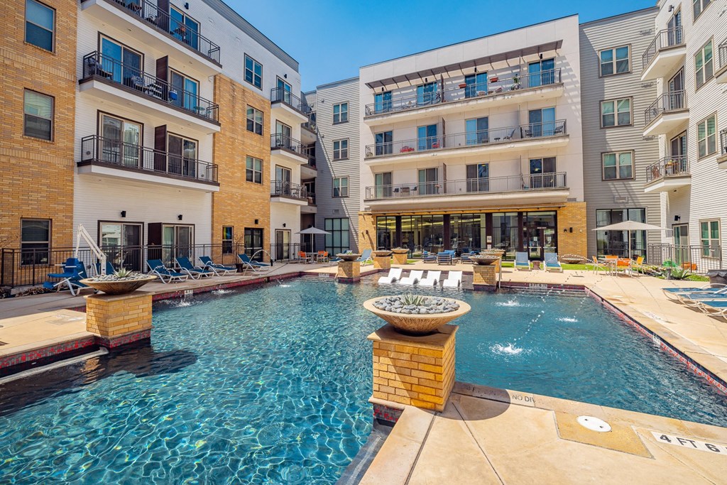 A large swimming pool in front of apartment buildings.