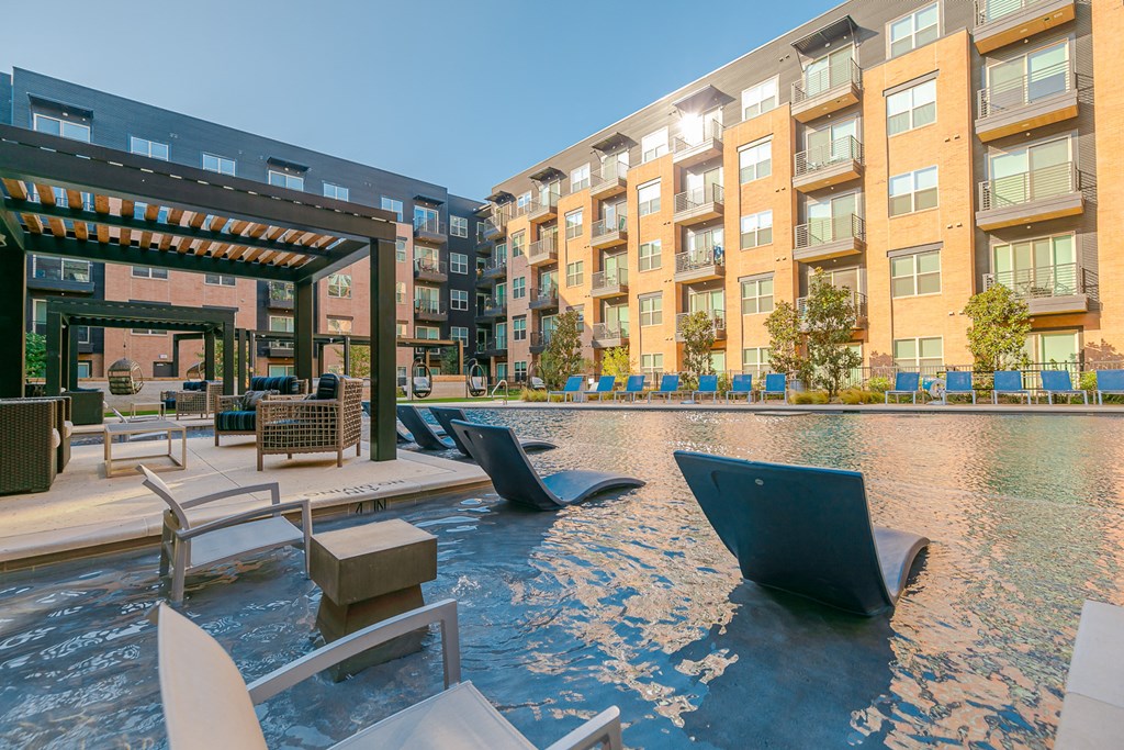 a swimming pool with lounge chairs in front of an apartment building
