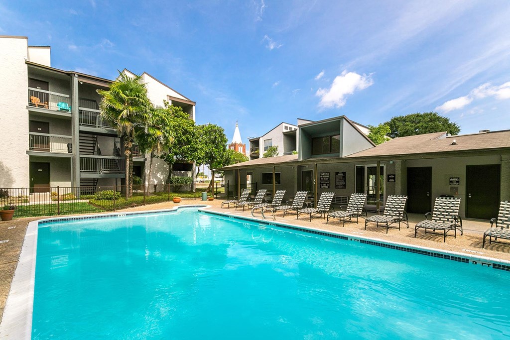a swimming pool with lounge chairs and a building in the background
