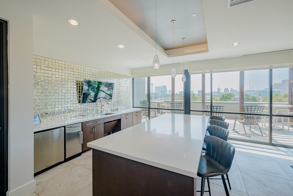 A kitchen with a long white counter and a view of the city.