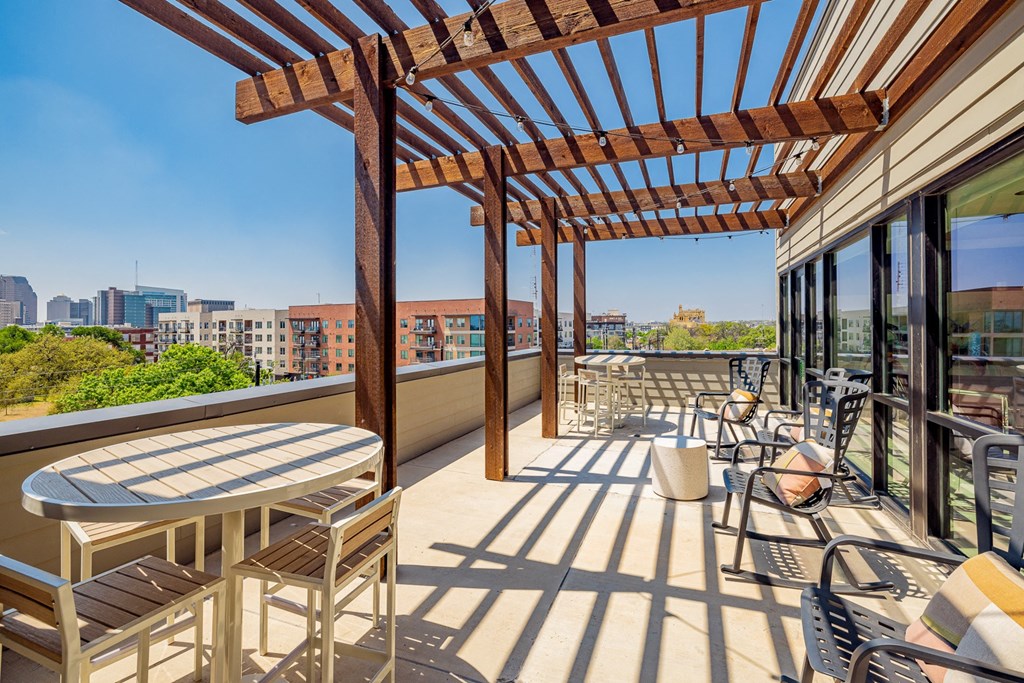 A wooden pergola over a patio with a table and chairs.