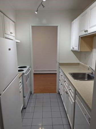 A kitchen with white cabinets and a white fridge.