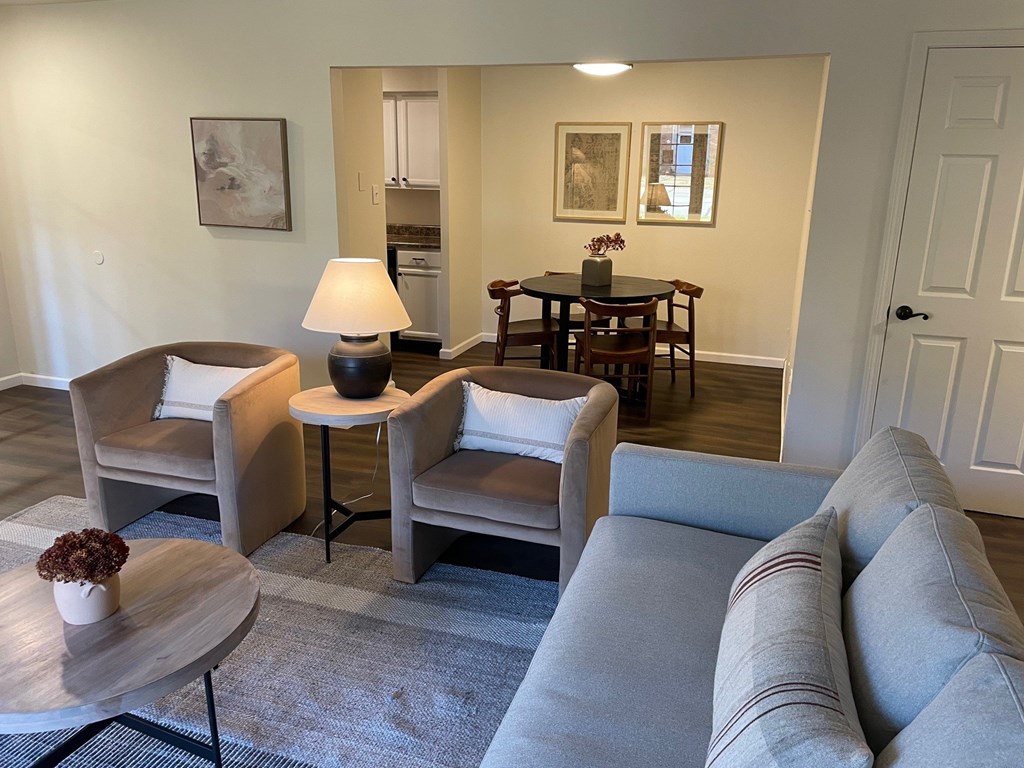 A living room with a grey couch, a wooden table, and a lamp.