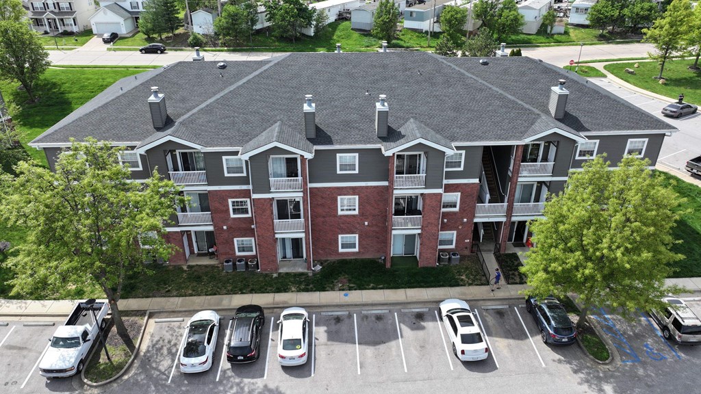 A large apartment complex with a parking lot in front.