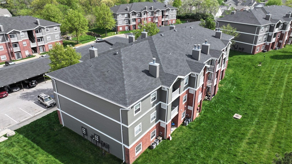 A large building with a grey roof and a parking lot in front.