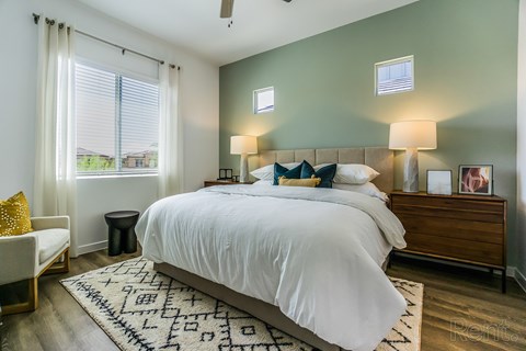 A bedroom with a large bed and a window with blinds.