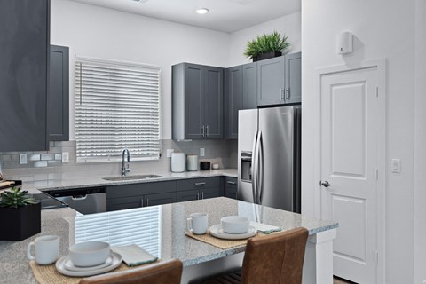 a kitchen with black cabinets and a table with plates and chairs