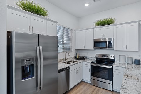 an open kitchen with stainless steel appliances and white cabinets