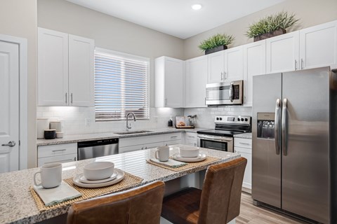 a kitchen with stainless steel appliances and a table with plates and chairs