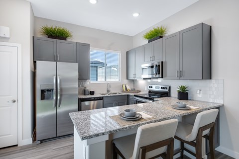 A modern kitchen with a granite countertop and stainless steel appliances.