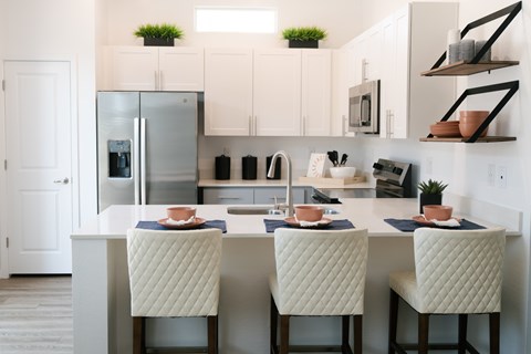 A kitchen with a table and chairs in the foreground and a refrigerator in the background.