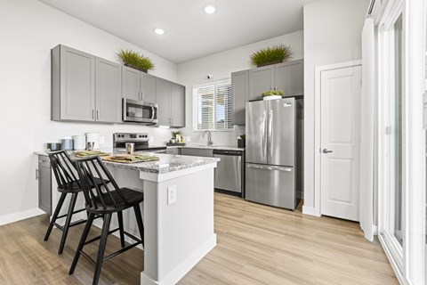 A kitchen with a white counter and a black bar stool.