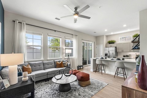 A modern living room with a grey sofa and a ceiling fan.