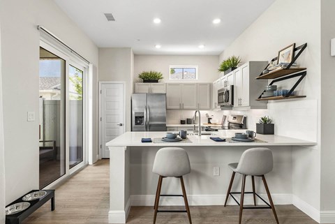 A kitchen with a white counter and bar stools.