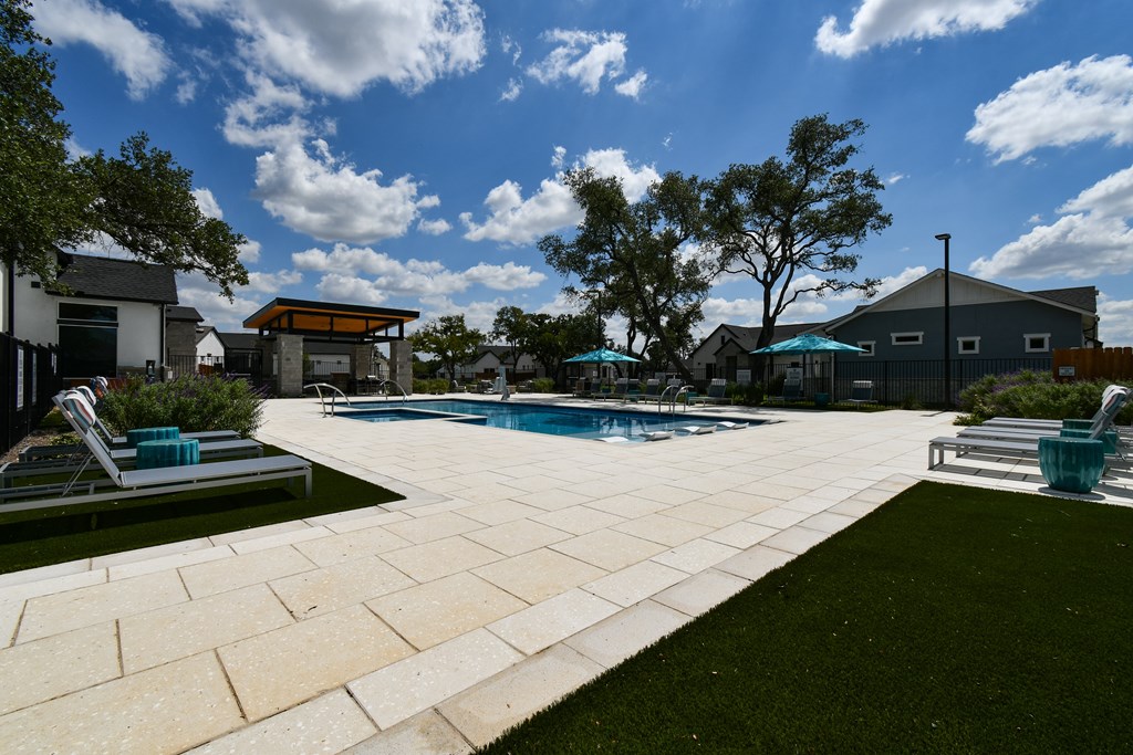 A swimming pool surrounded by a patio and lawn area.