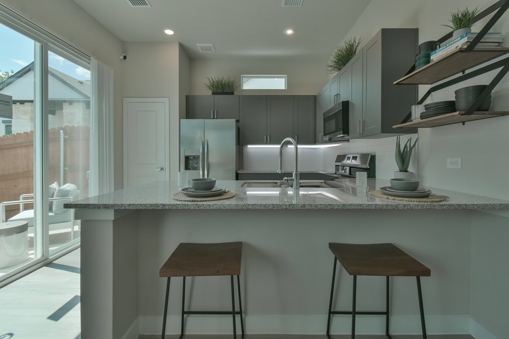 A modern kitchen with a bar stool in front of the island.