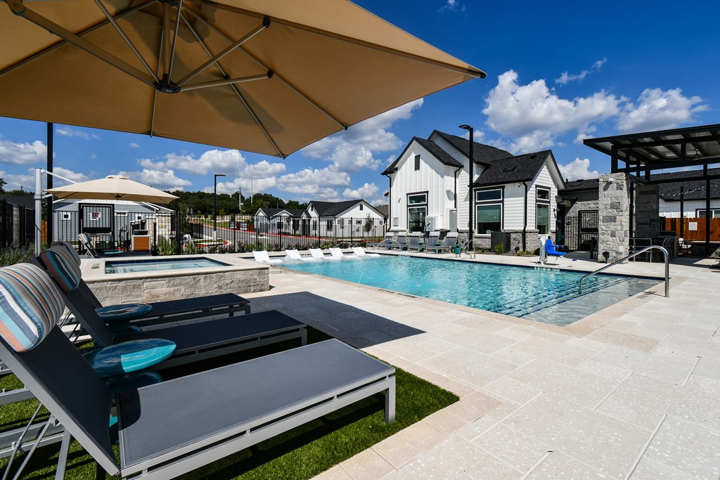 A sunny day at the pool with a striped lounge chair and umbrella.