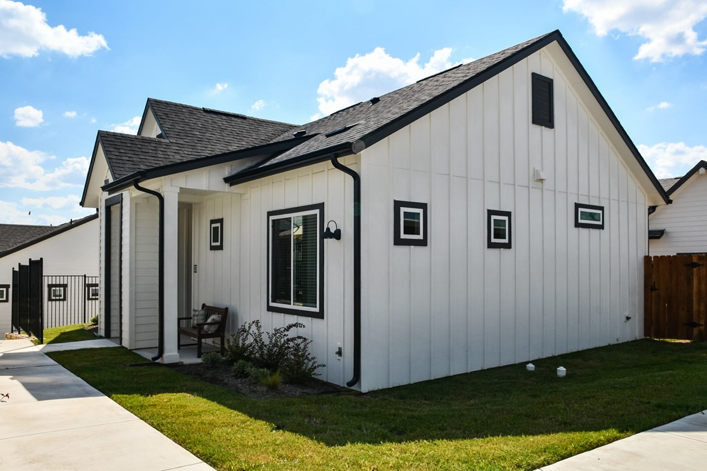 A white house with a black roof and a small porch.