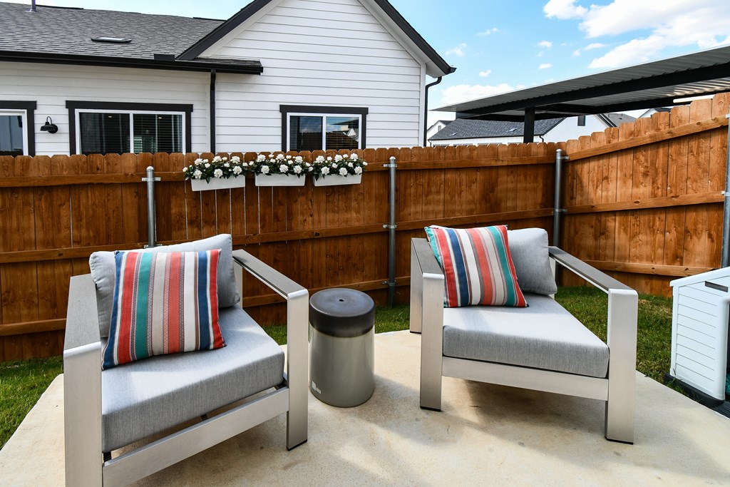 Two chairs with striped pillows are on a patio.