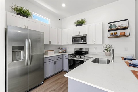 A modern kitchen with a stainless steel refrigerator and white countertops.