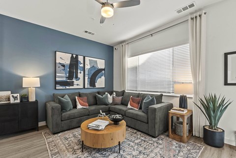 A living room with a grey couch, a coffee table, and a ceiling fan.