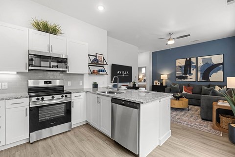 A modern kitchen with white cabinets and stainless steel appliances.