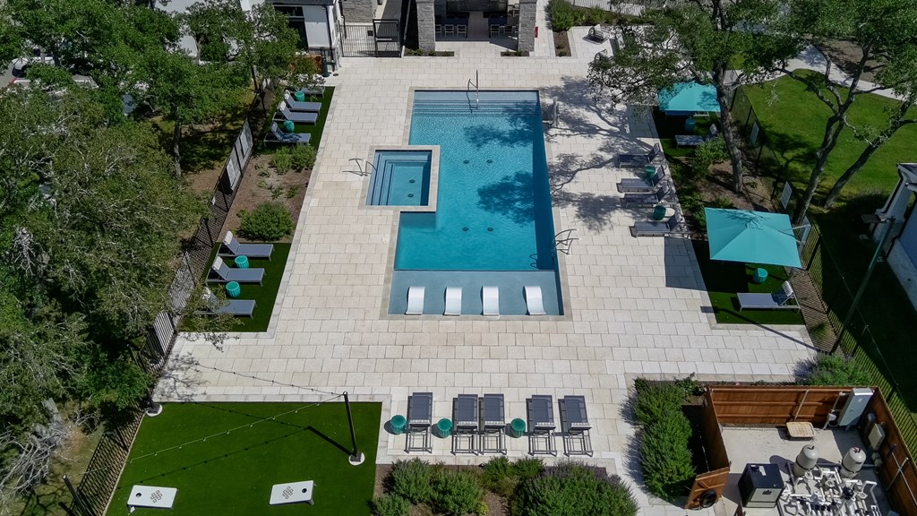 An aerial view of a backyard with a pool, patio furniture, and a small garden.