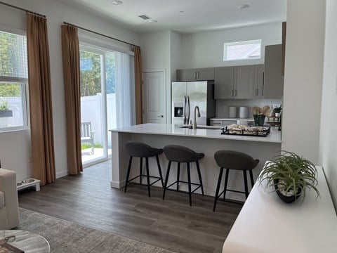 A kitchen with a bar stool and a plant on the counter.