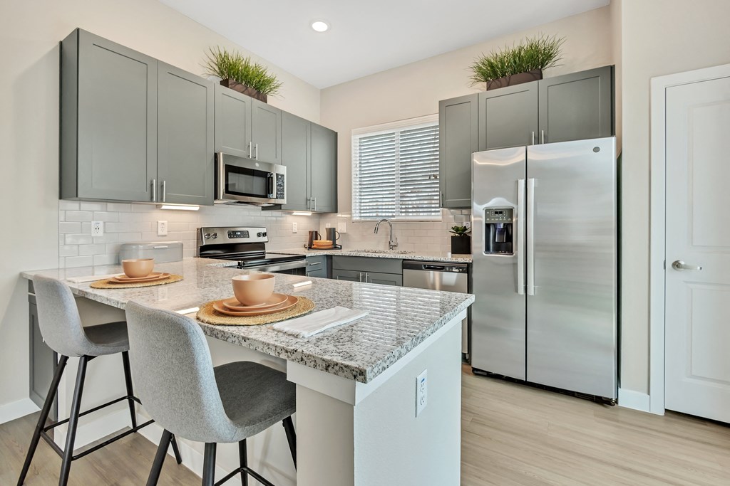 an open kitchen with stainless steel appliances and a marble counter top at Avilla Towne Center Apartments, Texas