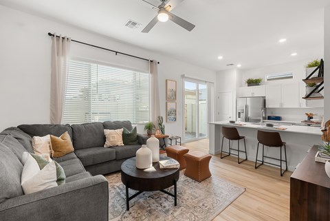 A living room with a grey couch, a coffee table, and a ceiling fan.