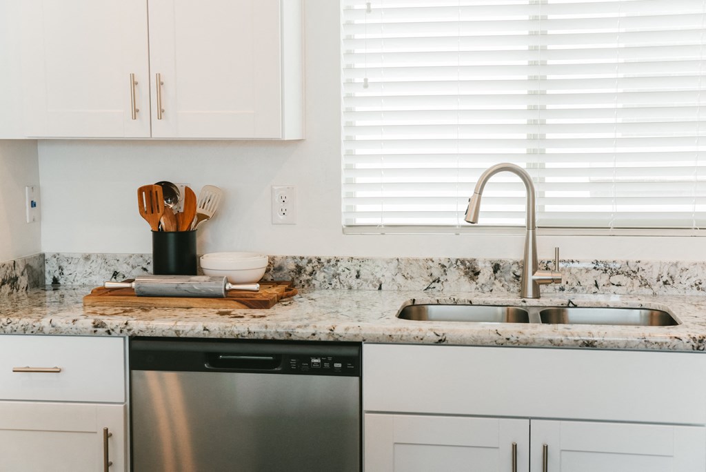 a kitchen with white cabinets and granite counter tops and a sink at Avilla Broadway Apartments, Phoenix, AZ