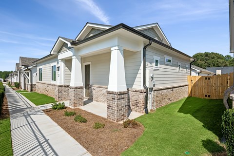 A white house with a grey roof and a green lawn in front.