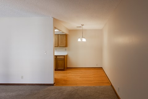 an empty living room with wood floors and a kitchen