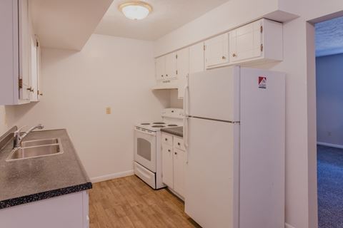 a kitchen with white appliances and a sink and refrigerator