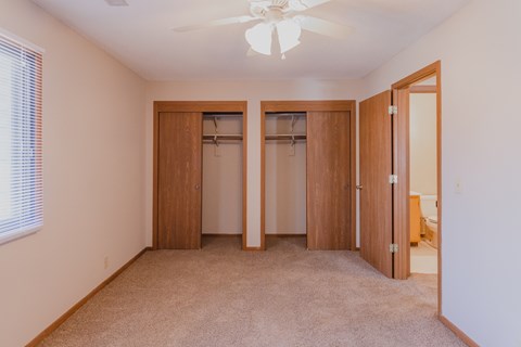 a bedroom with two closets and a ceiling fan